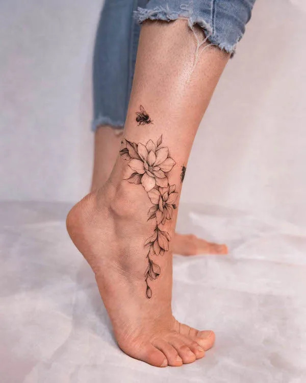 Bee and flowers foot tattoo in black and grey ink, proving the stunning potential of monochromatic artistry