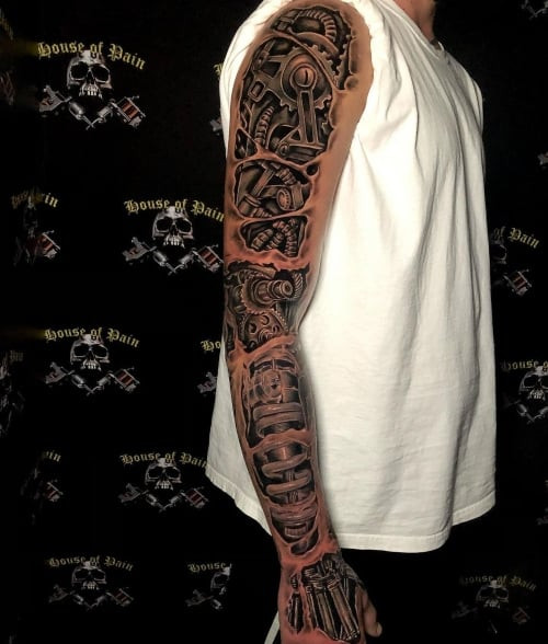 Biomechanical tattoo sleeve with gears and pistons on a man's arm