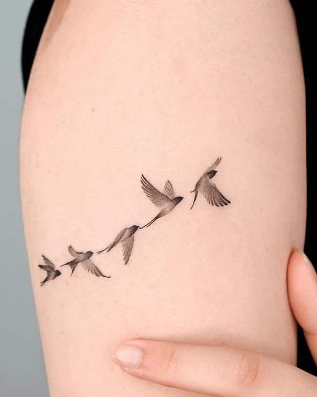 alt text: Birds taking flight tattoo on arm, symbolizing growth, freedom, and the strength found in personal transformation