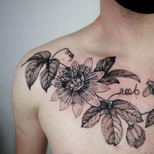 Botanical leaf and flower tattoo on a man's leg