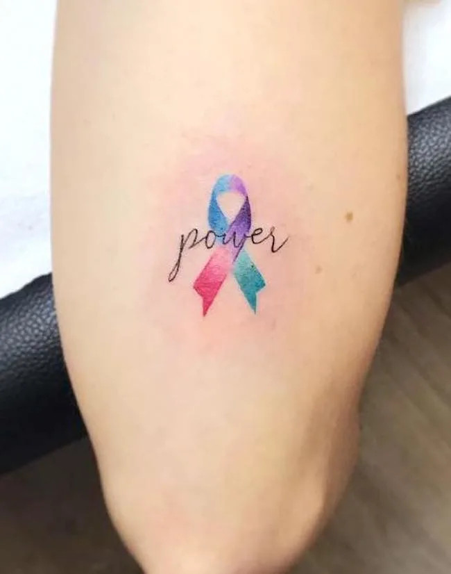 alt text: Pink ribbon breast cancer awareness tattoo with floral details, symbolizing survivor strength, courage, and triumph over adversity