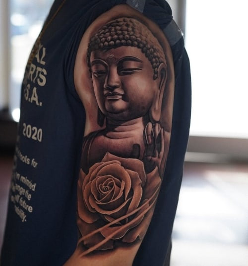 A Buddha face tattoo with serene expression on a man's arm, symbolizing peace