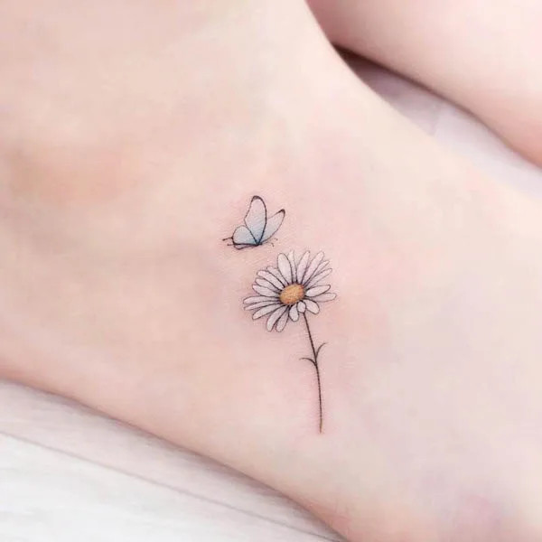 Girly foot tattoo featuring a butterfly and daisy design, symbolizing youth, purity, transformation, and beauty