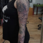 Close-up of the detailed cobweb tattoo with insects and lace elements