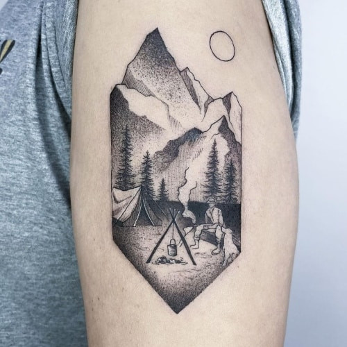 Camping scene tattoo with mountains and campfire on a man's leg