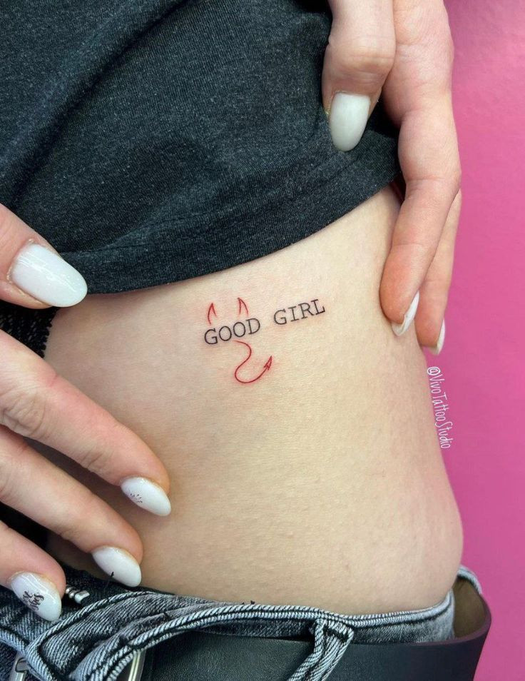 Minimalist Good Girl tattoo on the side with devil horns and tail design, close-up view.