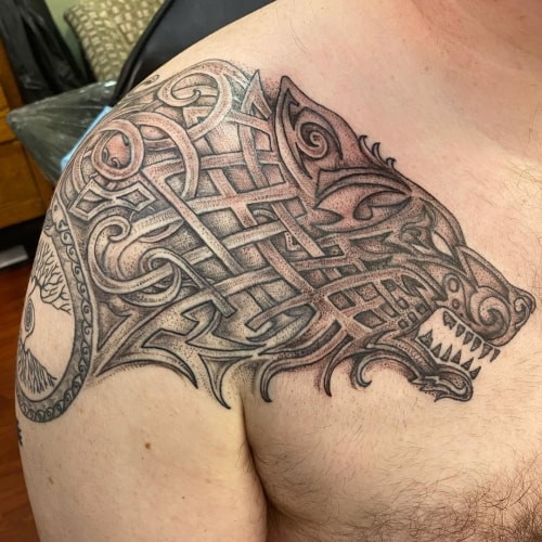 An intricate Celtic wolf tattoo on a man's shoulder, featuring traditional Celtic knots and spirals, symbolizing ancestral connection, protection, and heritage.