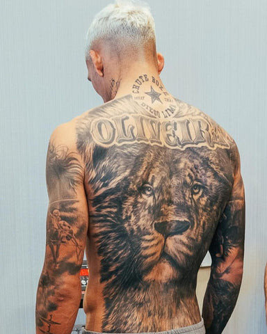 Bold Charles Oliveira back tattoo featuring a lion face and his surname, symbolizing strength, courage, and family ties.