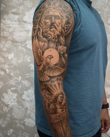 A Christian themed half sleeve tattoo featuring a cross and religious imagery.