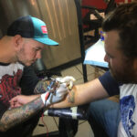 Close-up of Drew Wilson tattooing a trout on a forearm