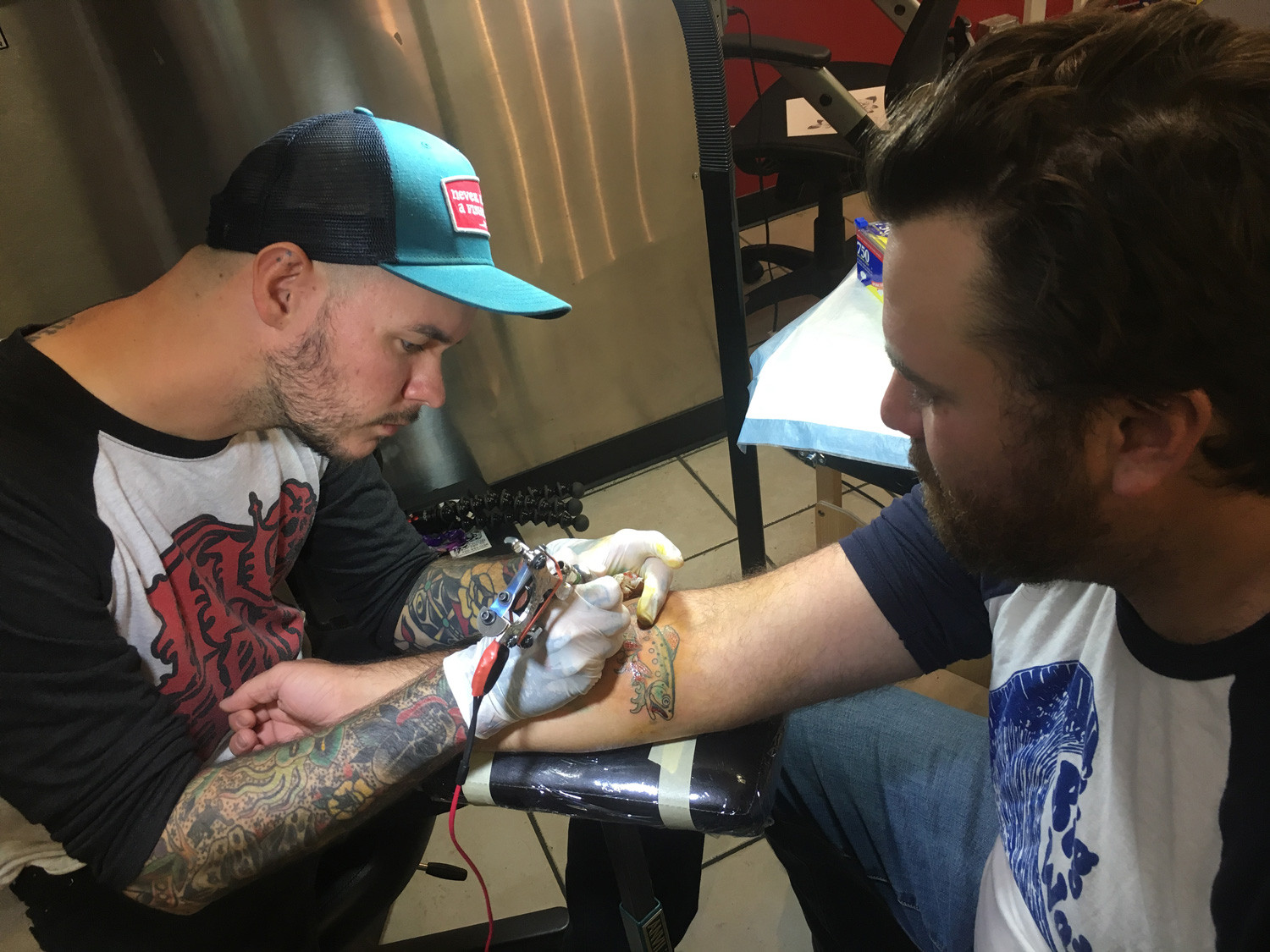 Close-up of Drew Wilson tattooing a trout on a forearm