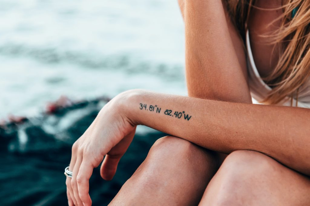 Close-up of a forearm tattoo featuring delicate script lettering, ideal for names or dates in a memorial design.