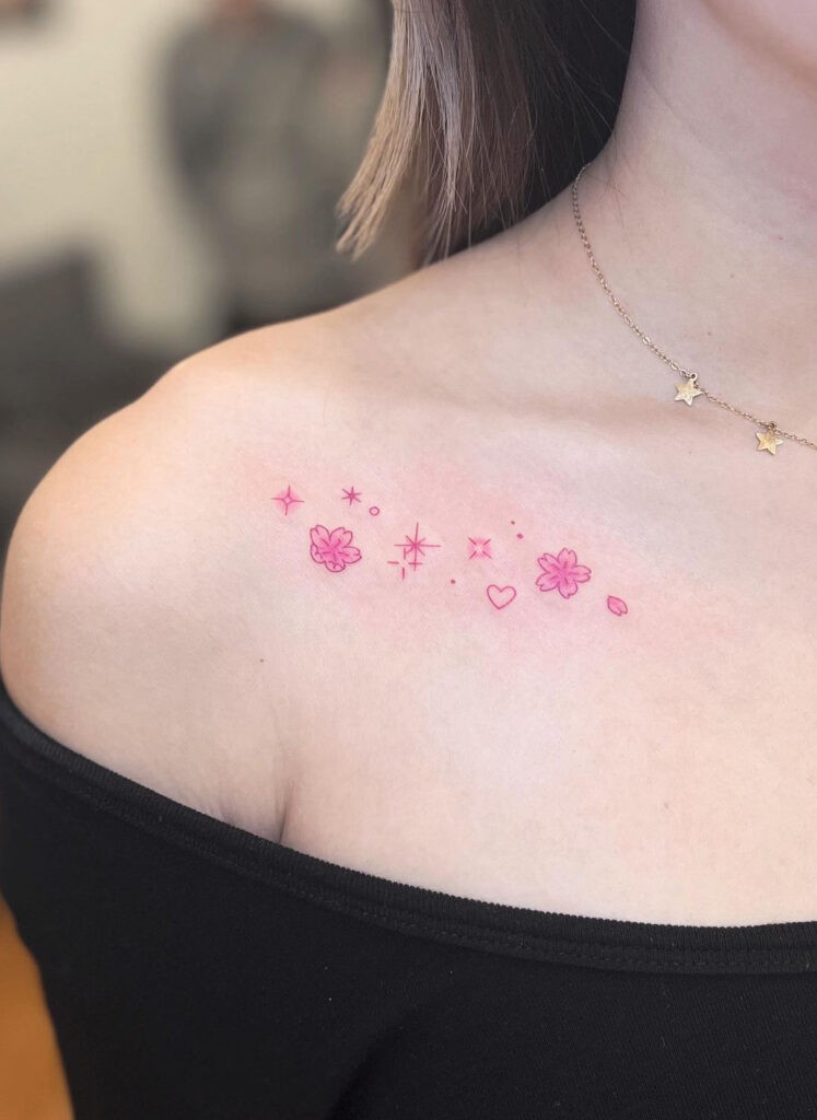 Red ink flowers, hearts and sparkles collarbone tattoo