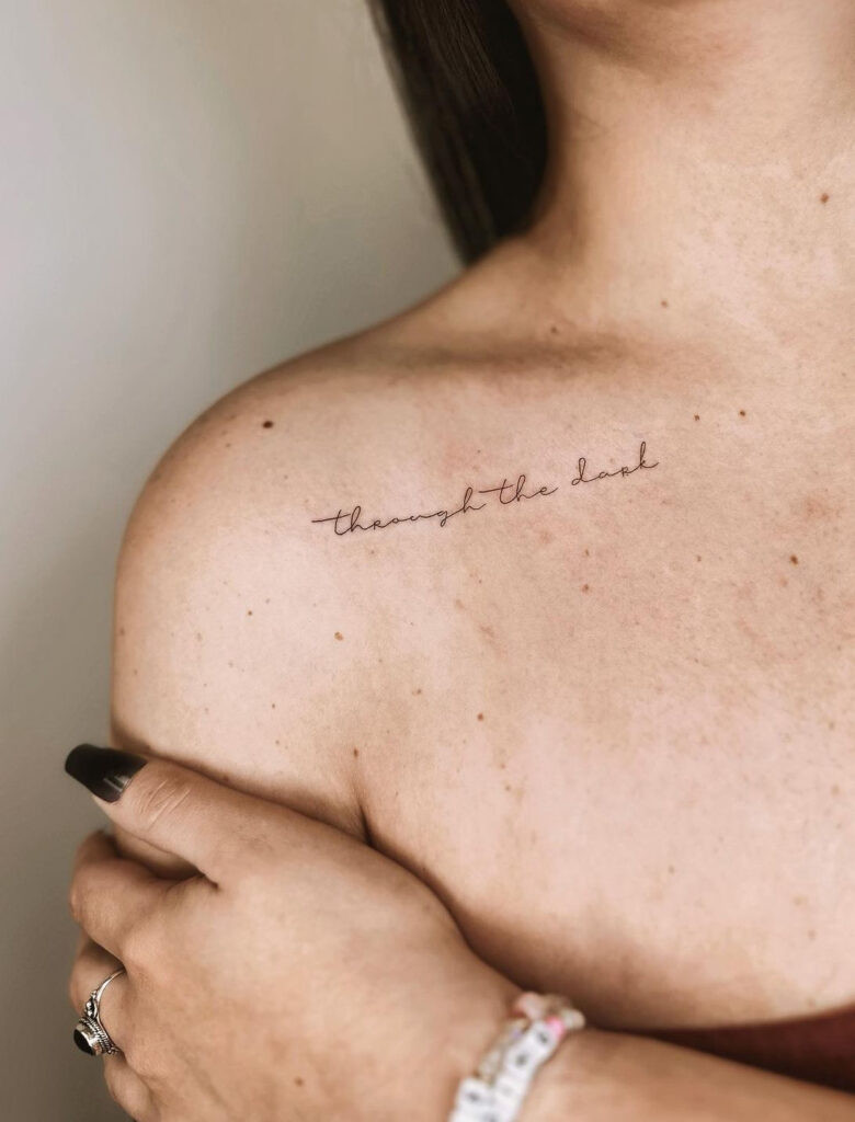 “through the dark” lettering collarbone tattoo