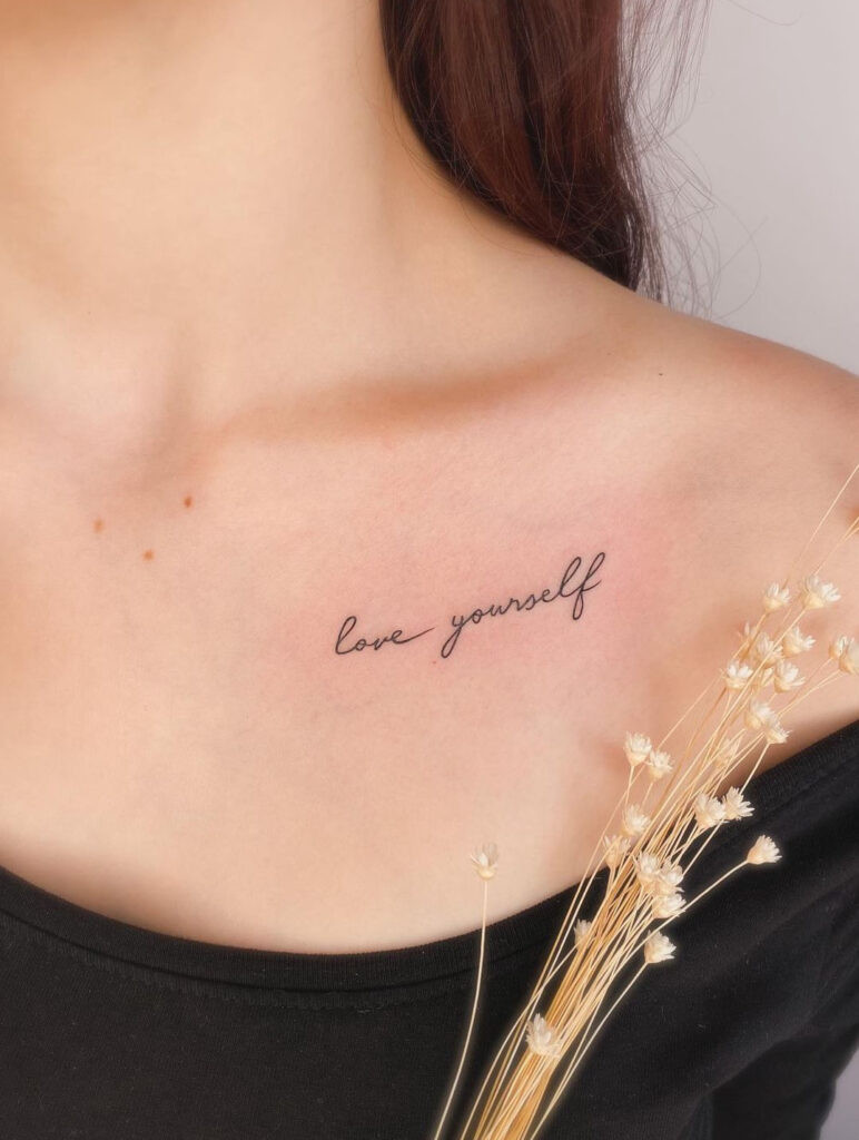 “love yourself” cursive collarbone tattoo