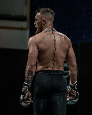 Unique Conor McGregor back tattoo featuring a vertical thorny helix, symbolizing sacrifice and endurance.