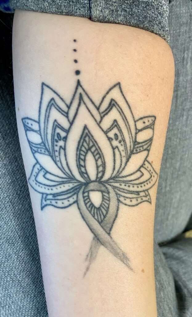 A lotus flower blooming from a gray brain cancer ribbon, symbolizing growth from adversity.