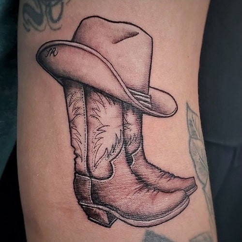 Black ink cowboy boot tattoo with spurs