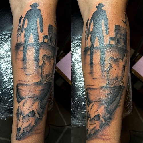 Cowboy silhouette tattoo against a sunset background