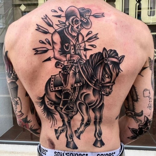 A cowboy riding a horse tattoo on a man's leg, dynamic and adventurous