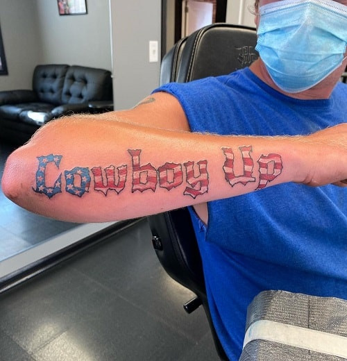 Black ink &quot;Cowboy Up&quot; lettering tattoo on forearm