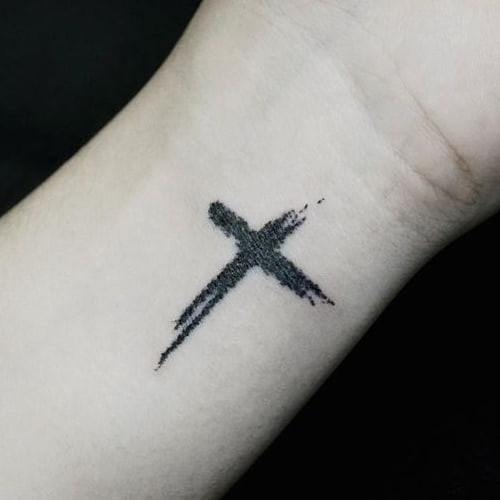 Minimalist cross tattoo on a man's finger