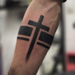 Detailed cross forearm tattoo in black ink