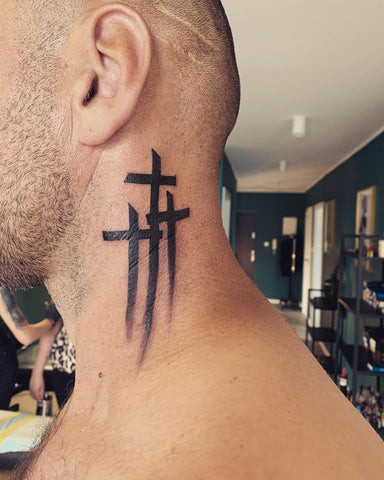 Detailed ornamental cross tattoo on a man's neck, intricate and decorative style.