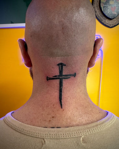 Bold black cross tattoo on the side of a man's neck, prominent and visible design.