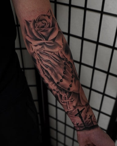 Detailed cross tattoo on a man's upper arm, showcasing intricate linework and shading.