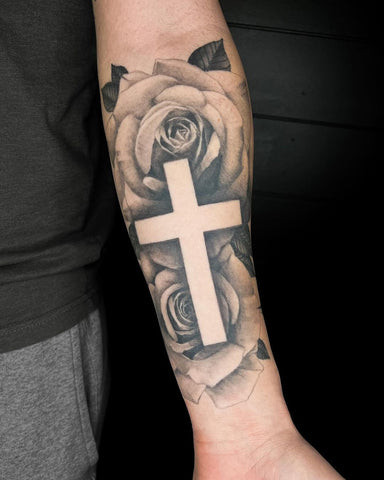 Simple outlined cross tattoo on a man's inner forearm, minimalist and understated design.