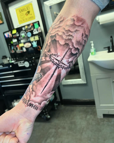 Geometric cross tattoo on a man's forearm, incorporating sharp lines and modern style.