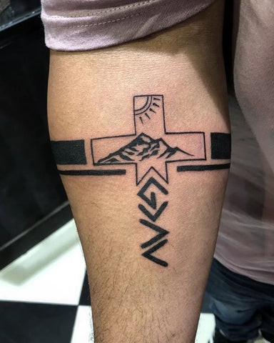 Detailed Celtic cross tattoo on a man's outer forearm, showcasing knotwork and intricate design.