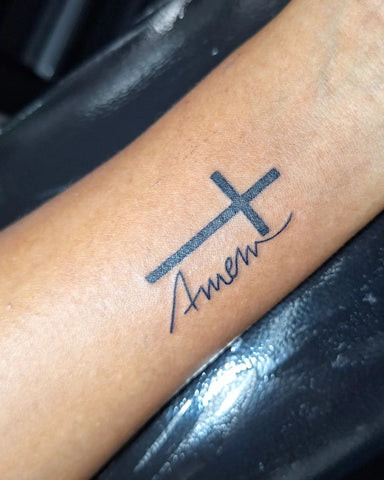 Delicate line work cross tattoo on a man's wrist, subtle and elegant design.