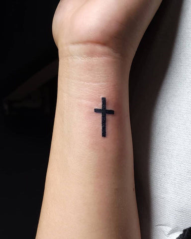 Simple cross tattoo on a man's wrist, clean lines and centered placement.