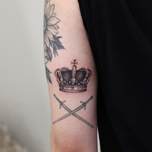 Two crown tattoos on men, one on the forearm with a realistic detailed crown and another on the hand with a minimalist crown outline.