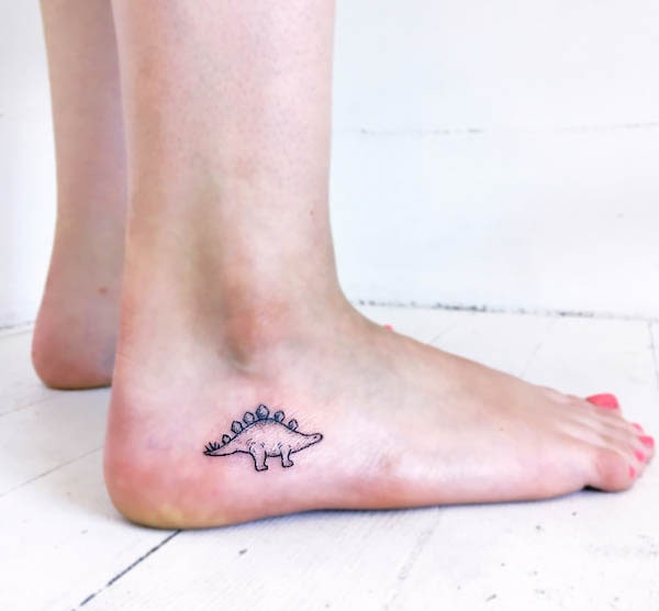 Cute small Stegosaurus foot tattoo, a playful and uniquely shaped dinosaur design fitting perfectly on the side of the foot