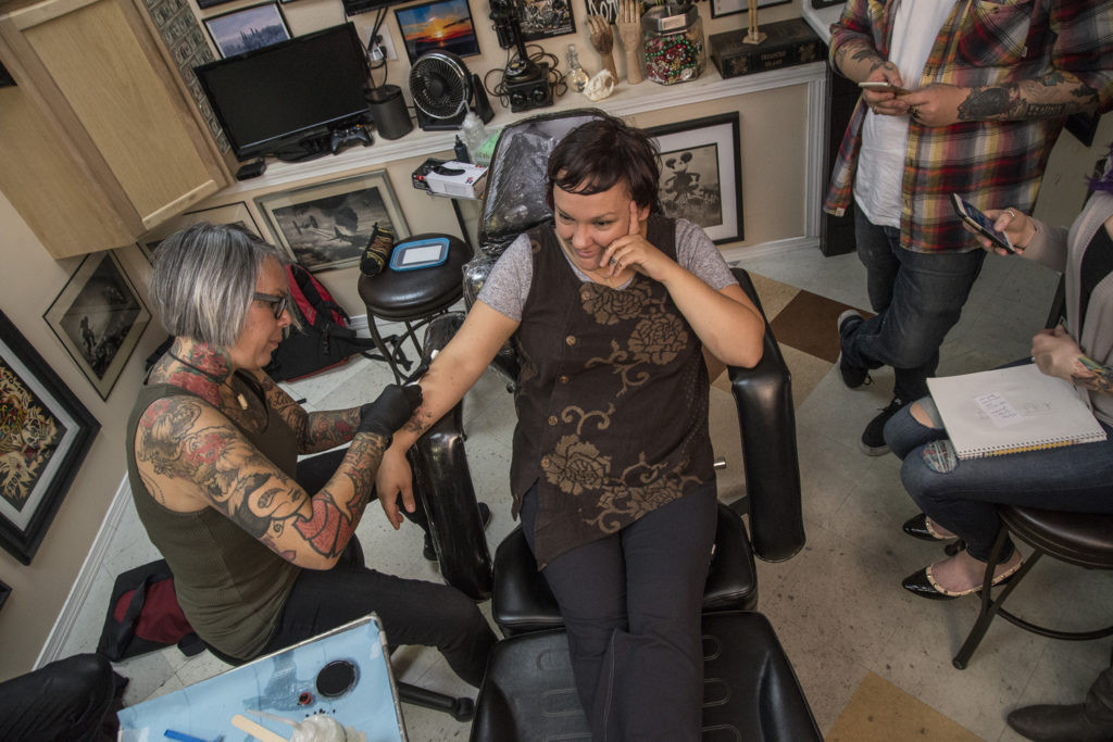 An Inuit tattoo artist, Maya Sialuk Jacobsen from Greenland, meticulously hand-tattoos Holly Mititquq Nordlum's chin using traditional techniques.