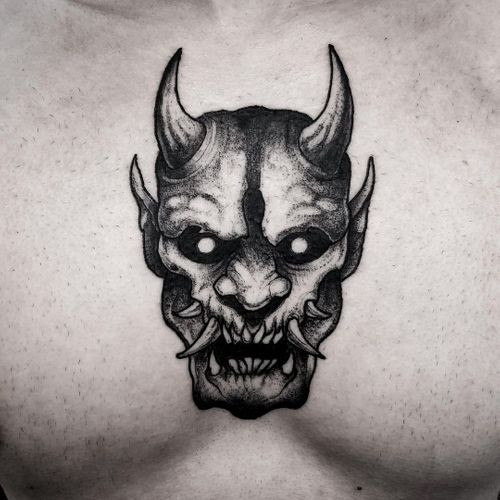 Stylized demon mask tattoo on the arm, a striking men tattoo idea.