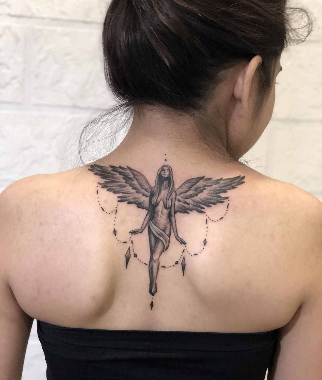 Unique sexy angel tattoo for women, flowing design emphasizing body contours on the upper back