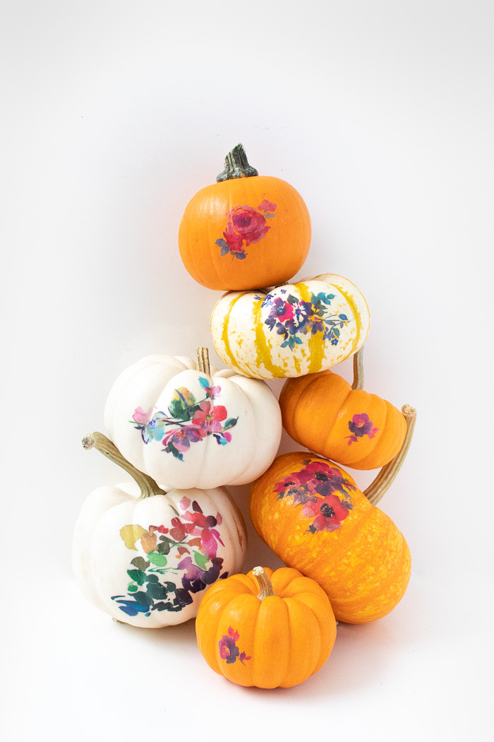 Mini pumpkins decorated with watercolor floral temporary tattoos, displayed as fall decor.