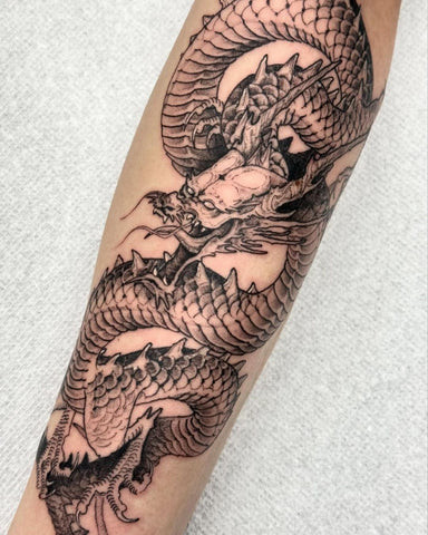 Dragon forearm tattoo drawing with bold lines and mythical symbolism.