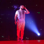 Drake performing onstage displaying tattoos