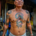 An Iban tattoo artist meticulously hand-tapping a traditional design.