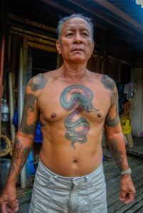 An Iban tattoo artist meticulously hand-tapping a traditional design.