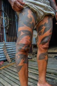 An Iban elder proudly displaying his traditional hand tattoos, a testament to a lifetime of experiences.