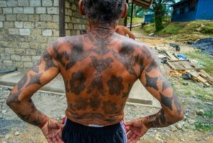 An Iban man in Entalau proudly displaying his traditional hand tattoos, connecting to his heritage.