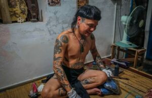 Boy Skrang preparing the traditional hand-tapping tools and ink for the tattoo process.