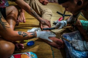 Boy Skrang preparing to tattoo the traditional fish hook design on the author's ankle.