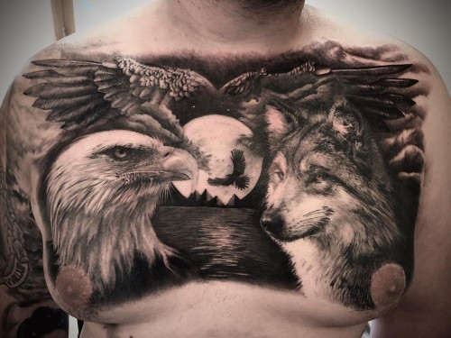 An eagle and wolf tattoo on a man's upper arm, depicting both animals in dynamic poses, symbolizing balance in nature, courage, power, and patriotic pride.